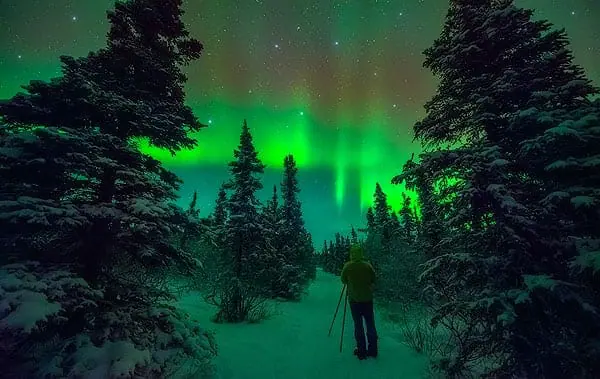 photographer taking pictures of of the northern lights in Alaska